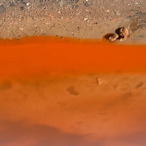 Imagen de la laguna con arena y aguas de color anaranjado