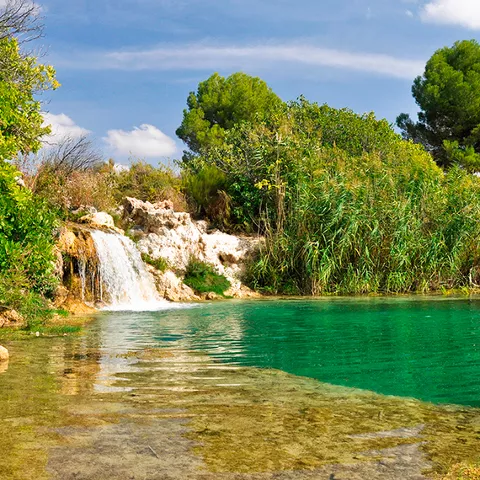 Imagen de una cascada sobre laguna en entorno verde