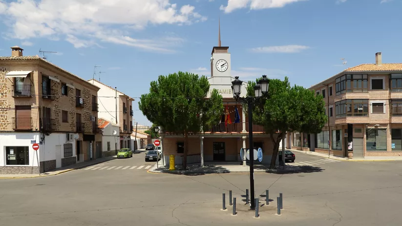 Casa consistorial con reloj, árboles y plaza abierta