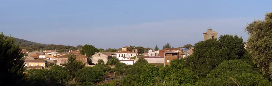 Vista del pueblo entre árboles y campos secos