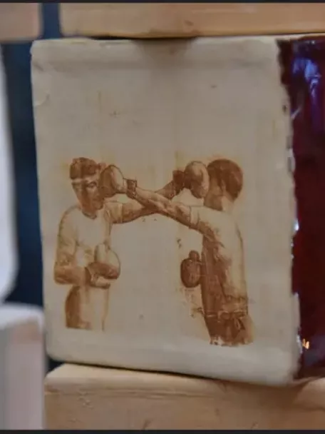 Imagen de una pieza de barro con unos boxeadores