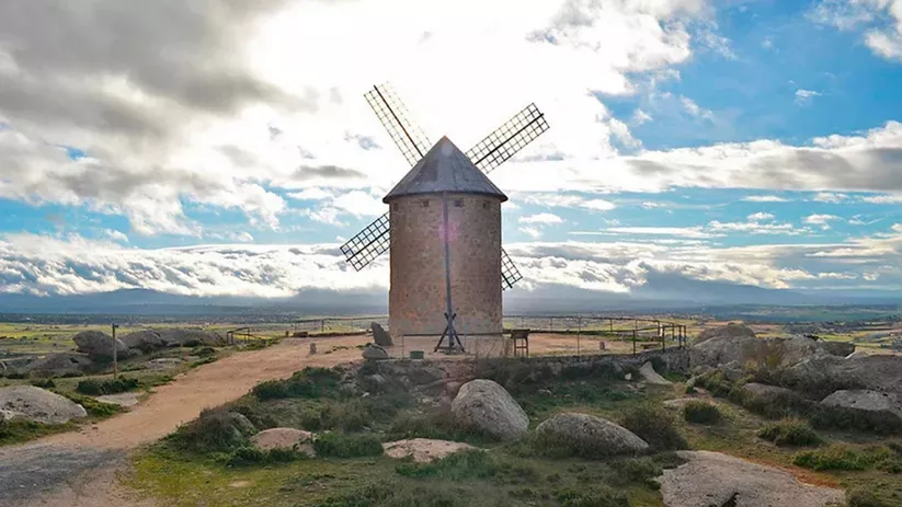 Molino de piedra en una loma con nubes al fondo