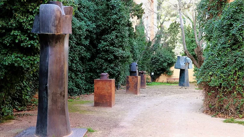 Conjunto de esculturas abstractas alineadas a lo largo de un camino rodeado de vegetación.
