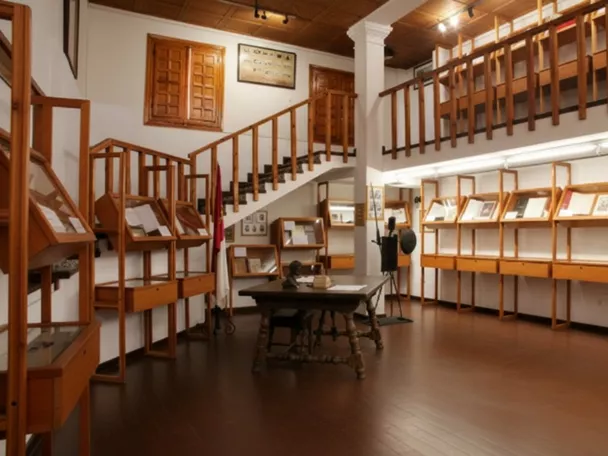Sala de museo con vitrinas de madera, mesa central y balcón interior.