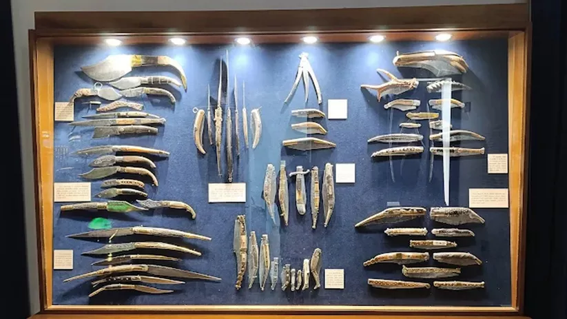 Vitrina de museo con colección de cuchillos antiguos expuestos y organizados.