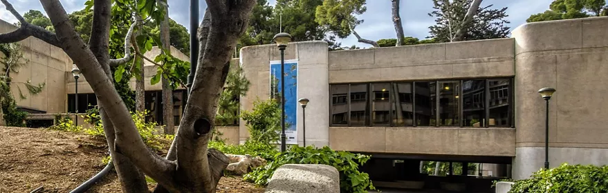 Edificio cultural de hormigón integrado en un entorno ajardinado con árboles.