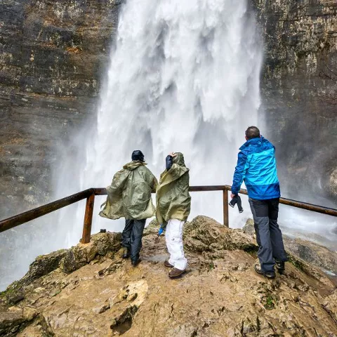Imagen de tres personas observando la cascada del nacimiento del río