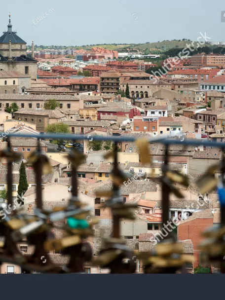 TOLEDO, SPAIN - APRIL 24, 2018: Cityscape in Toledo with view of the Tavera Hospital and locks hooked to a fence by lovers as a proof of eternal love in the foreground.