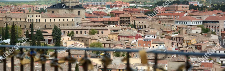TOLEDO, SPAIN - APRIL 24, 2018: Cityscape in Toledo with view of the Tavera Hospital and locks hooked to a fence by lovers as a proof of eternal love in the foreground.