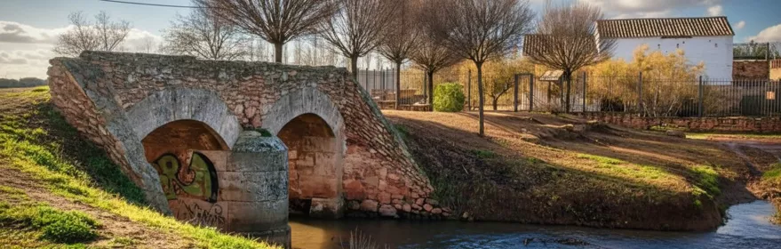 Puente antiguo de piedra sobre el río Azuer en Membrilla (Ciudad Real), entorno natural junto al cauce.