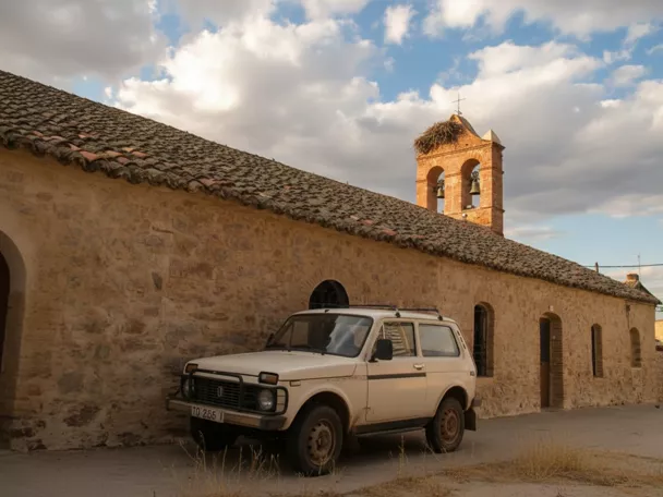 Iglesia parroquial de San Bartolomé en Navalpino (Ciudad Real), templo de piedra con espadaña y nido de cigüeñas.
