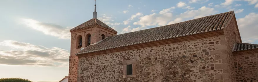 Iglesia parroquial de San Juan Bautista en Picón (Ciudad Real), templo de piedra con plaza adoquinada.