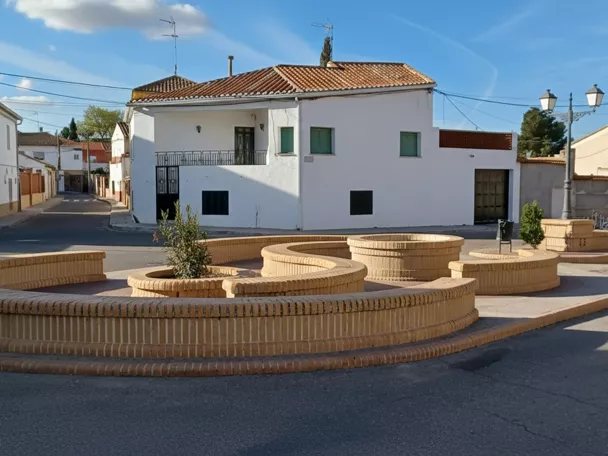 Plaza con jardineras circulares y casas blancas alrededor