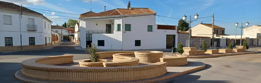 Plaza con jardineras circulares y casas blancas alrededor