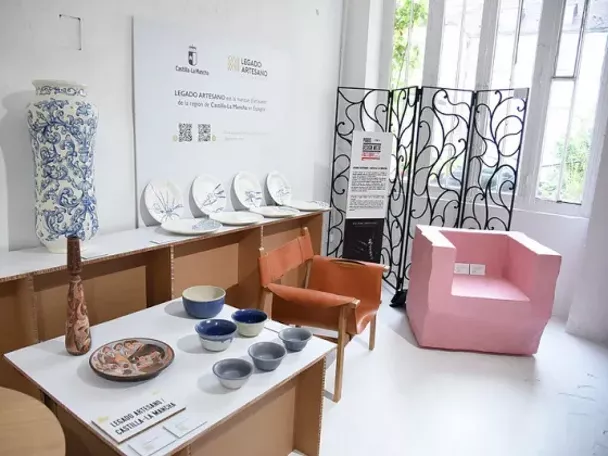 Imagen del stand en la galería con sillones y piezas de cerámica