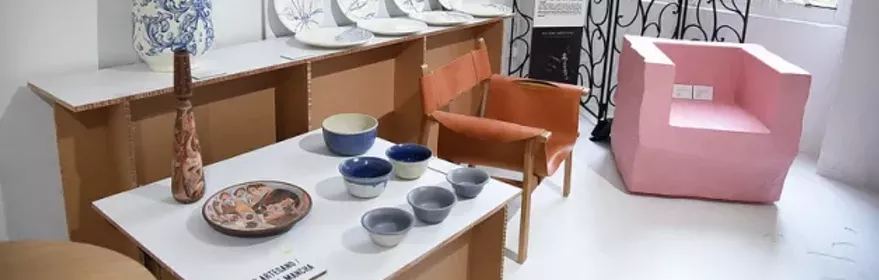 Imagen del stand en la galería con sillones y piezas de cerámica