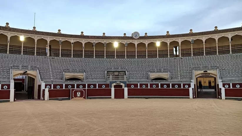 Vista frontal de graderío con barreras numeradas y arena central.