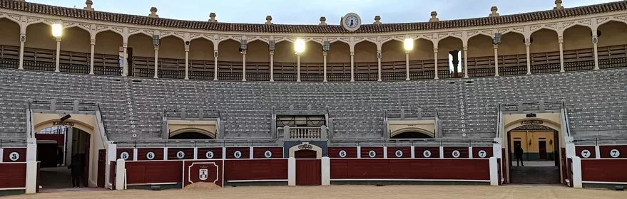 Vista frontal de graderío con barreras numeradas y arena central.