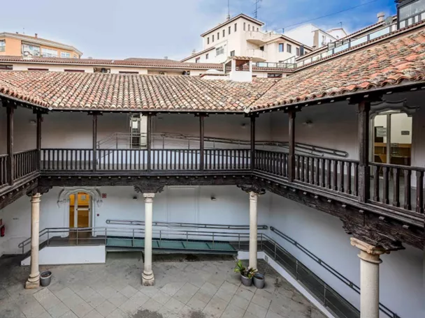 Galería interior con barandillas de madera alrededor de un patio central.
