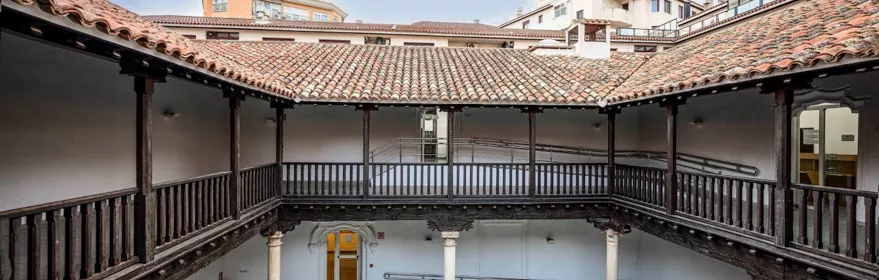 Galería interior con barandillas de madera alrededor de un patio central.