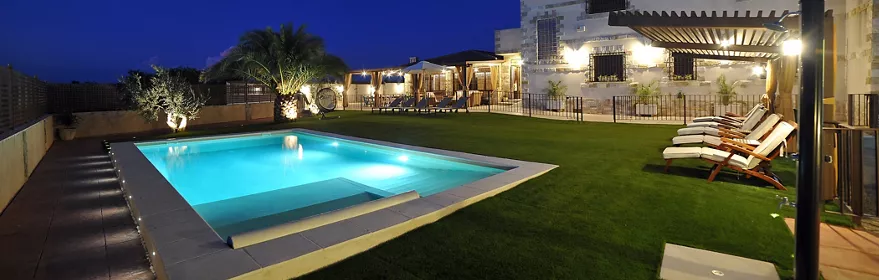 Vista exterior nocturna de Casa Rural Alma del Tajo, casa rural de 5 estrellas en Albarreal de Tajo (Toledo), con piscina privada, amplios jardines y zonas exteriores para grupos y familias.