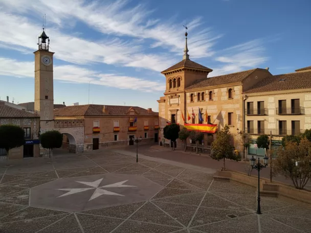 Plaza amplia con torre del reloj y edificio porticado