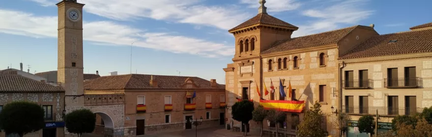 Plaza amplia con torre del reloj y edificio porticado