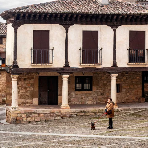 Imagen de una plaza de Atienza con una mujer y un perro