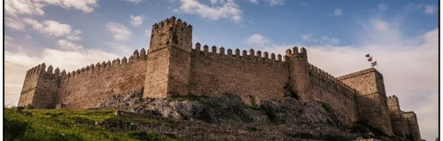 Castillo de piedra sobre ladera con cielo nublado