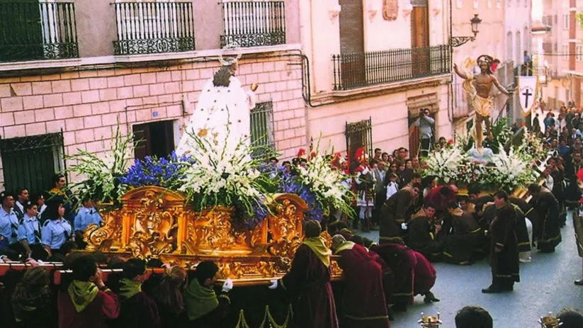 Procesión con paso dorado y gran afluencia de público en calle estrecha.