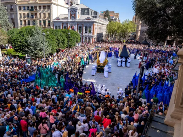 Desfile procesional con varios pasos y numerosos asistentes en plaza amplia.