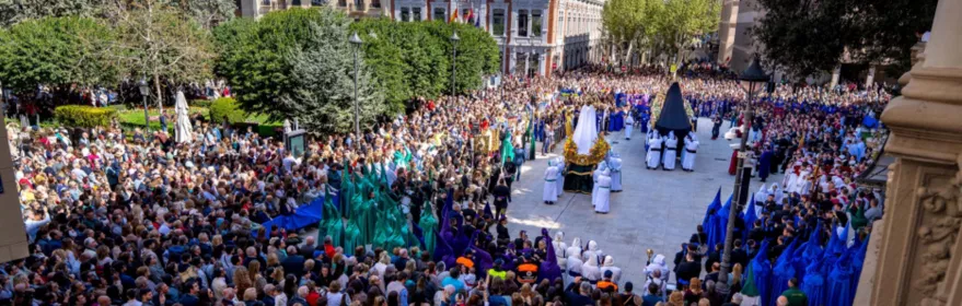 Desfile procesional con varios pasos y numerosos asistentes en plaza amplia.