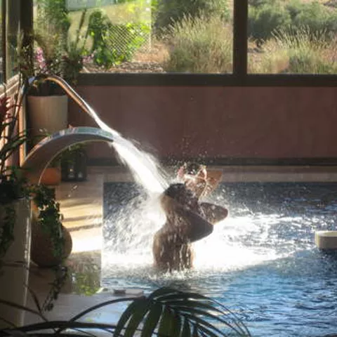 Imagen de dos personas en el spa bajo chorros en piscina