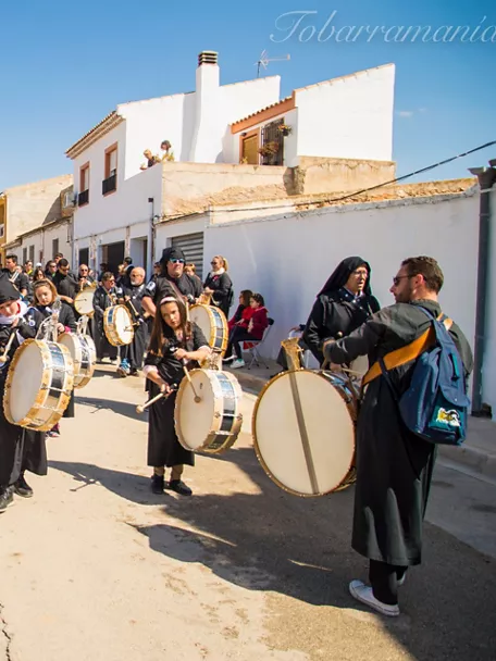 Niños y adultos tocando tambores en una celebración popular al aire libre.