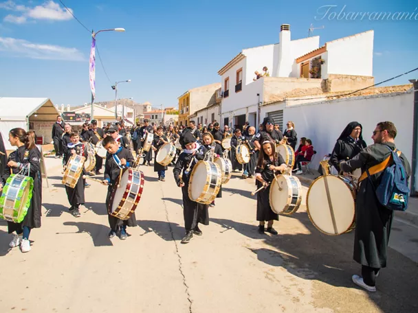 Niños y adultos tocando tambores en una celebración popular al aire libre.
