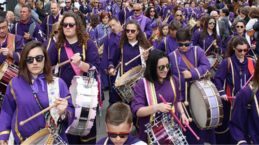Multitud de tamborileros vestidos de morado concentrados en una calle.