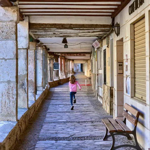 Una niña corre por los soportales de la calle Mayor de Tendilla