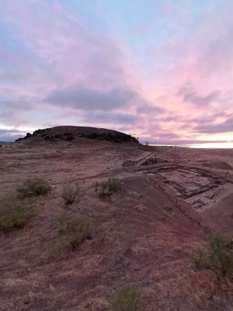 Restos arqueológicos al atardecer en un paisaje abierto.