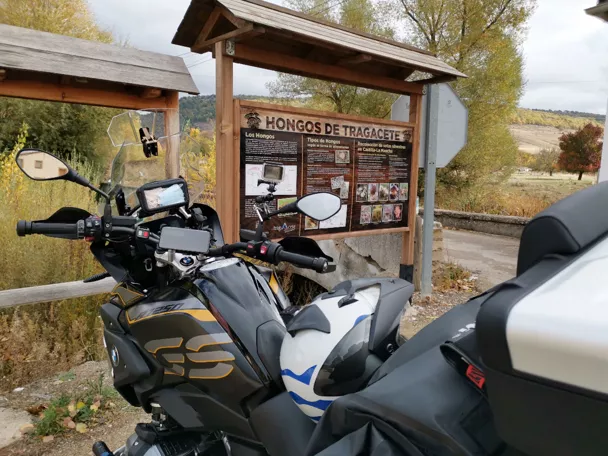 Imagen de una moto parada en un cartel de hongos de Tragacete