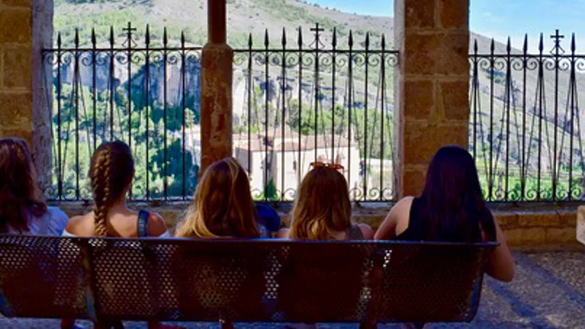 Imagen de chicas sentadas en un banco viendo el paisaje