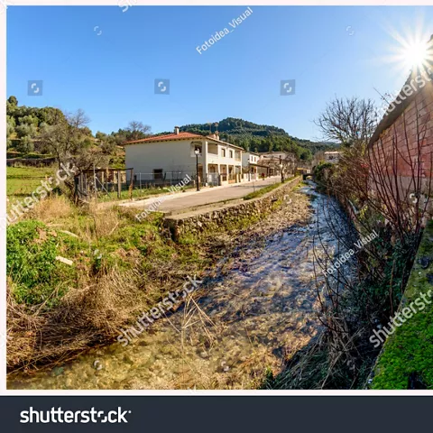 Imagen de un camino con riachuelo a un lado y casas