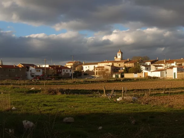 Vista panorámica de Peñascosa con casas tradicionales y campos de cultivo al atardecer.