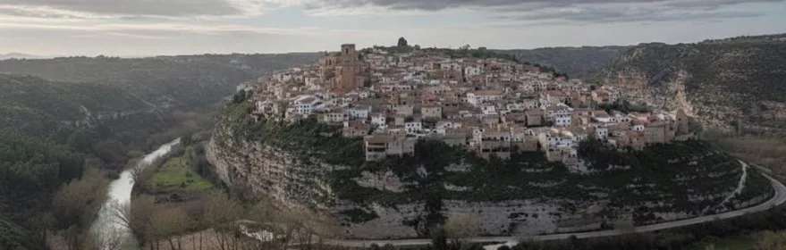 Vista aérea de Madrigueras asentada sobre un cerro junto al río Júcar, rodeada de paisaje natural y vegetación.