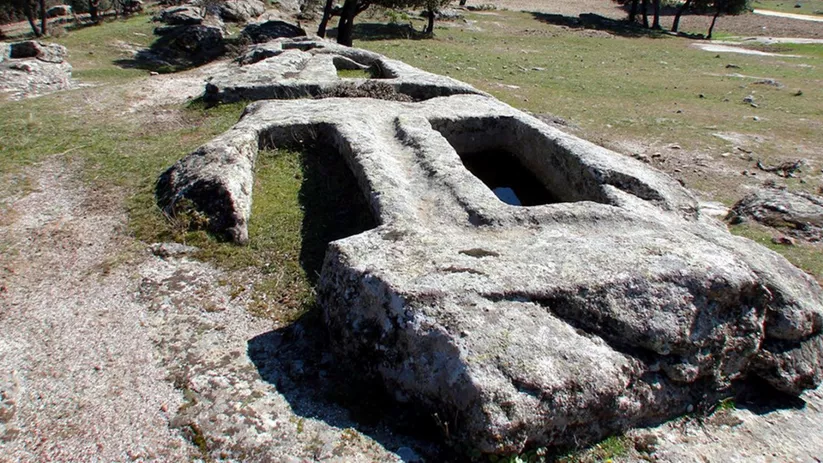 Tumbas antropomorfas excavadas en roca en entorno rural.