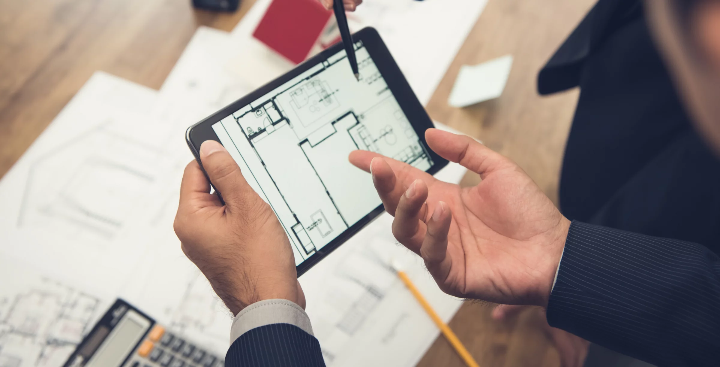 Real estate agent with client or architect team checking a housing model and its blueprints digitally using a tablet