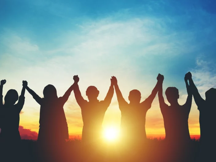 Silhouette of group business team making high hands over head in sunset sky