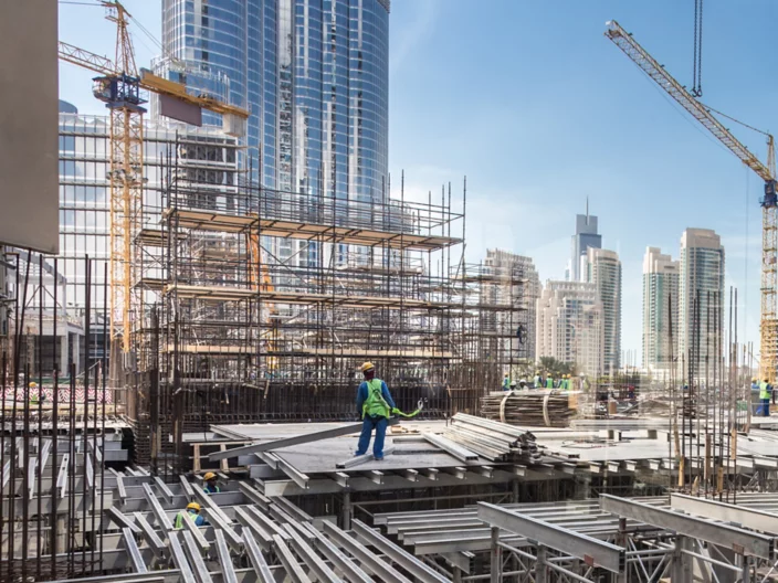 Laborers working on modern constraction site works in Dubai. Fast urban development consept