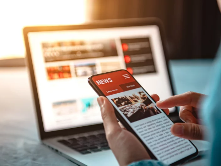 Online news on a smartphone. Mockup website. Woman reading news or articles in a mobile phone screen application at home. Newspaper and portal on internet.