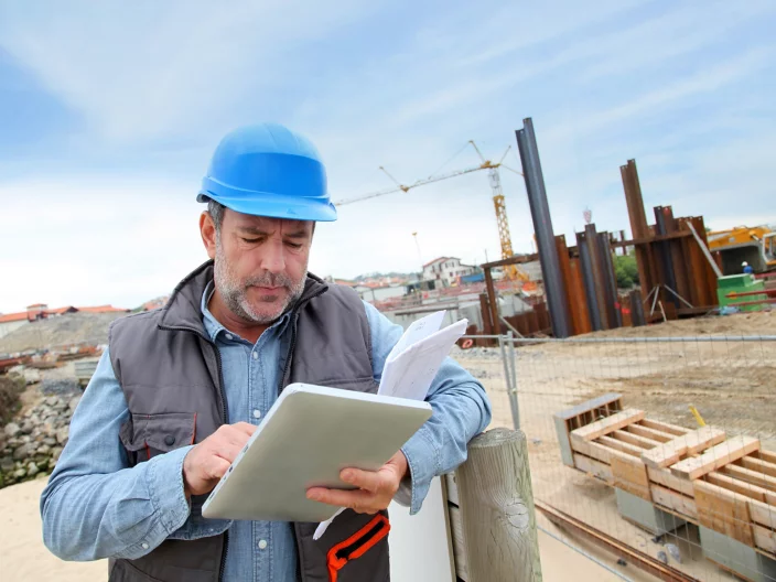 Construction manager controlling building site with plan