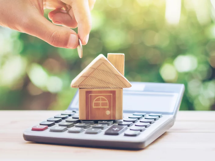 House is placed on the calculator. hand that is coin down the house. planning savings money of coins to buy a home concept for property, mortgage and real estate investment. savings to buy a house.